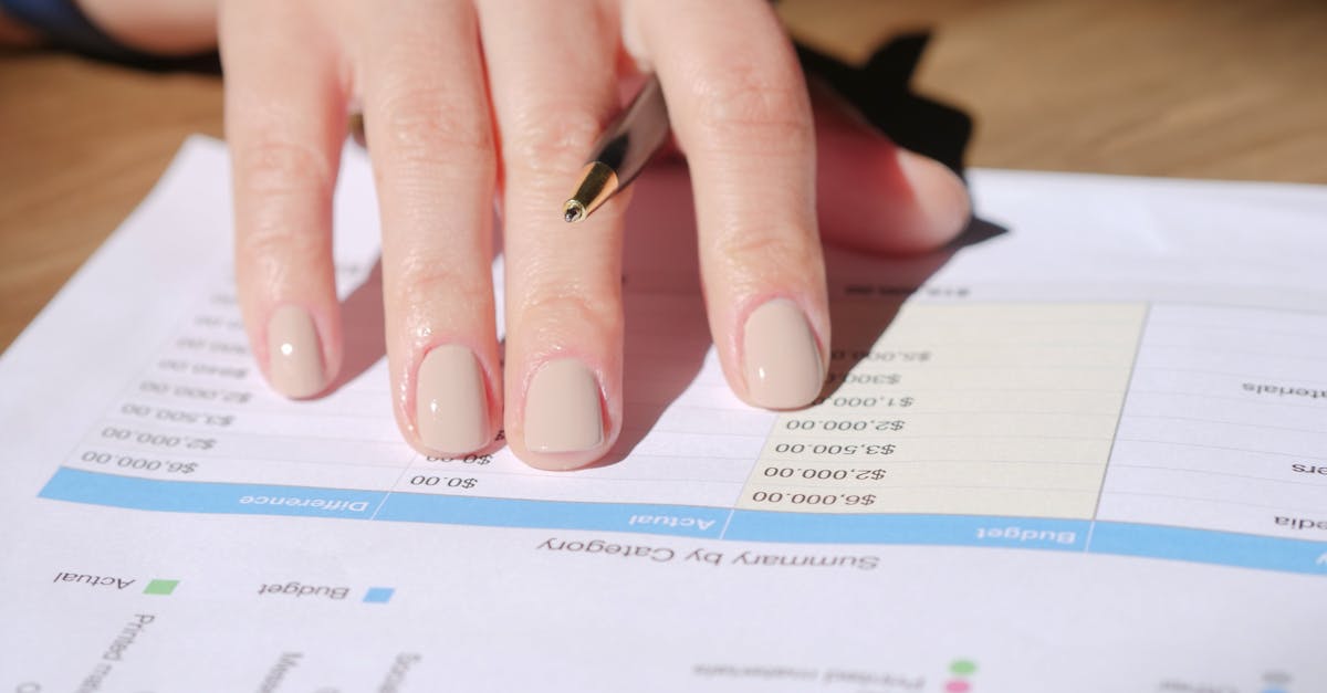 a hand writing on a financial document with a pen in a sunlit office space showing graphs and data
