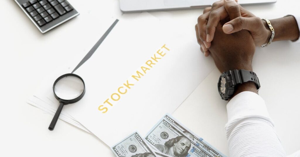hands folded over stock market documents with calculator and cash on desk