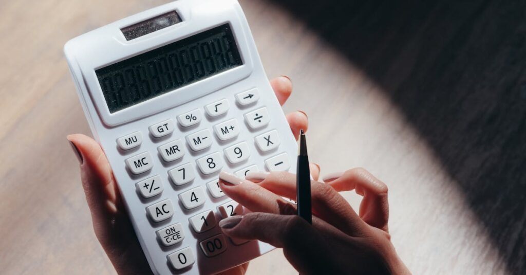 hands holding a calculator and pen for financial calculations in a well lit setting